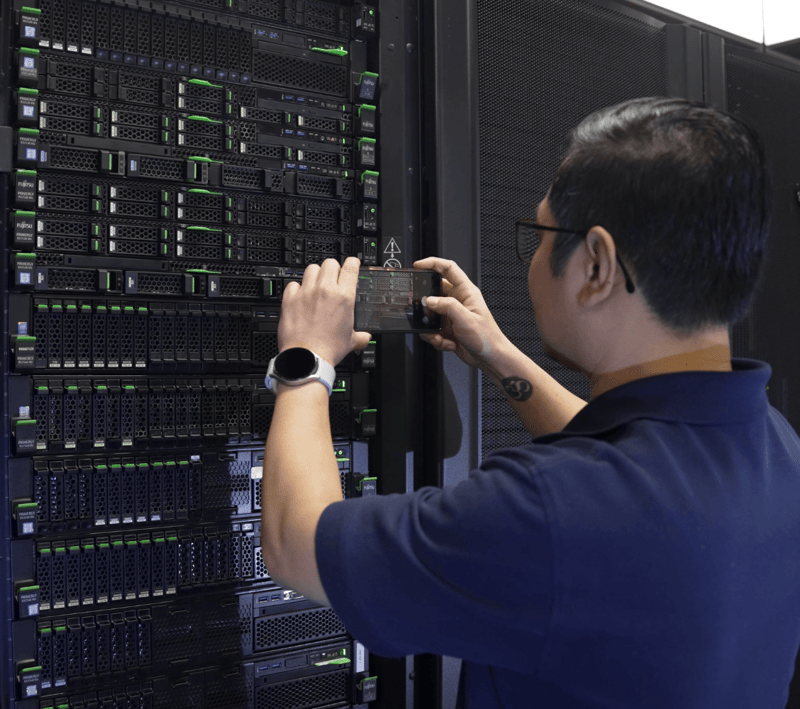 services technician taking picture on phone of data center rack job completion