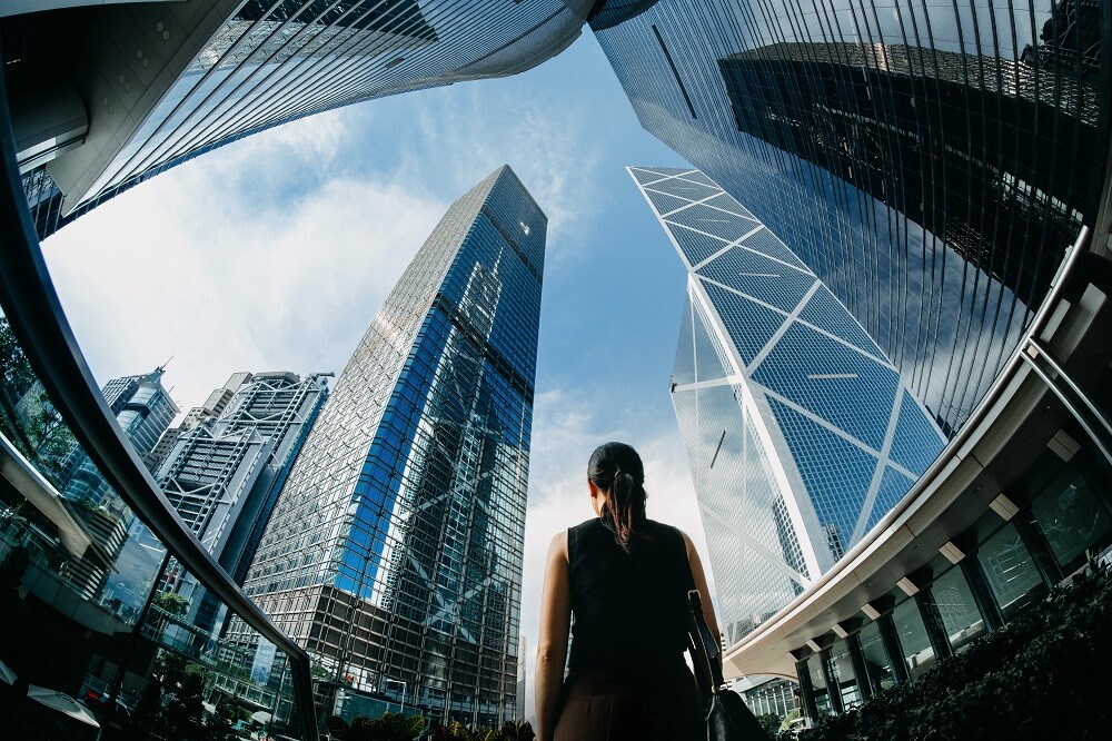 woman looking up tall buildings architecture-innovation-scalability