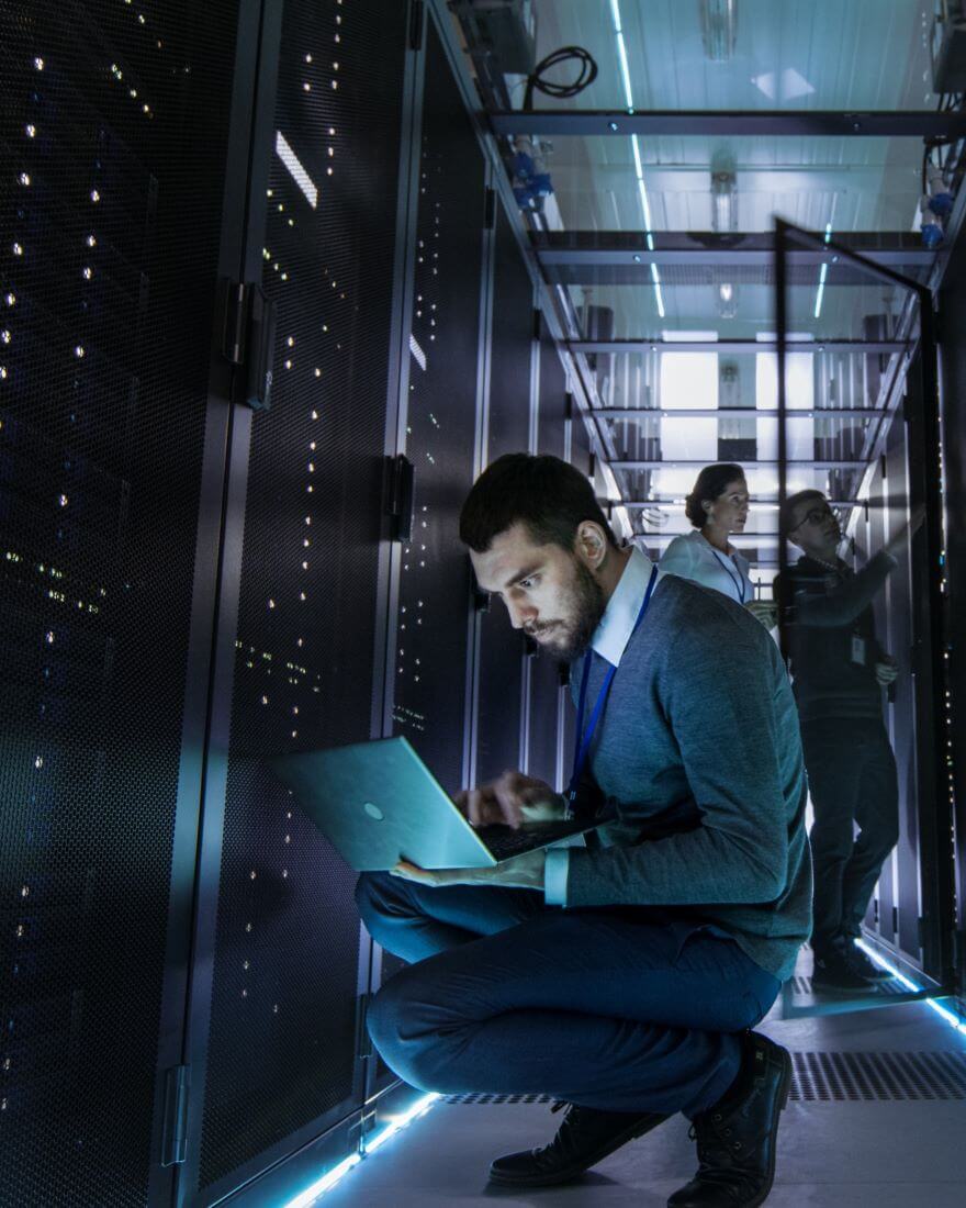 man-using-laptop-kneeling-down-working-in-data-center-server-room